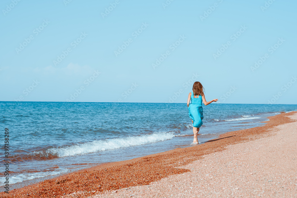girl in a dress runs along the seashore