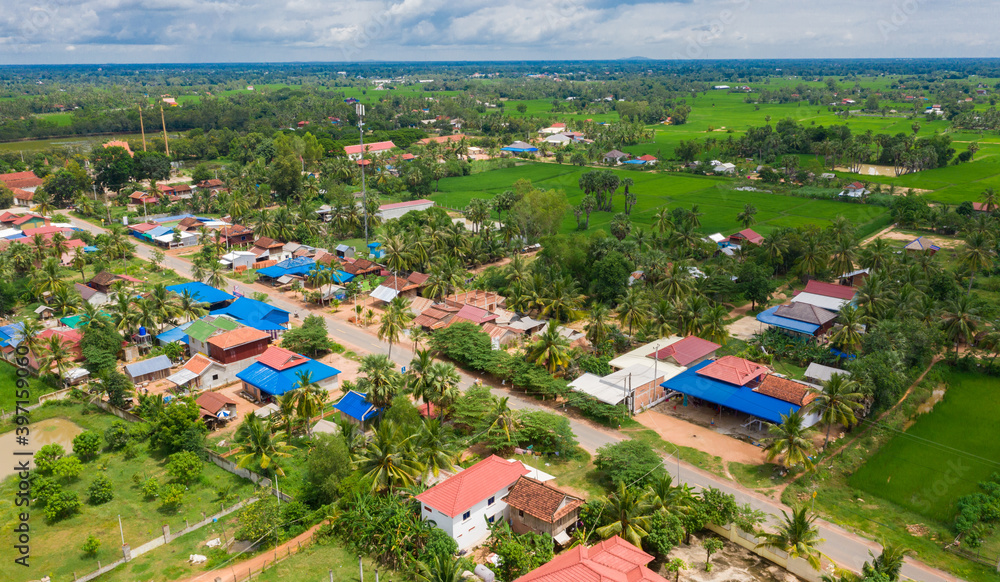 Fototapeta premium Main dirt road in rural village in Cambodia. There are houses on either side of the road.