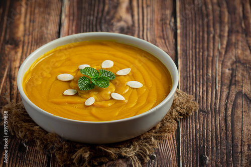 pumpkin soup in white bowl placed on wooden floor.