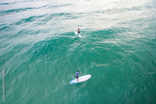 aerial view of two stand up paddle boarders in tropical ocean