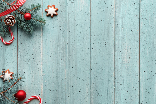 Zero Waste low impact Christmas background with copy-space. Xmas flat lay, top view on mint blue wooden background. Frame from natural fir twigs, candy canes, pine cones, star cookies and red trinkets