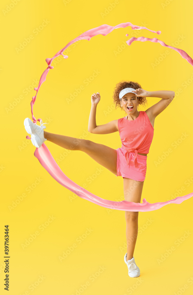 Young African-American woman doing aerobics and splash of paint on color background Young African-American woman doing aerobics and splash of paint on color background