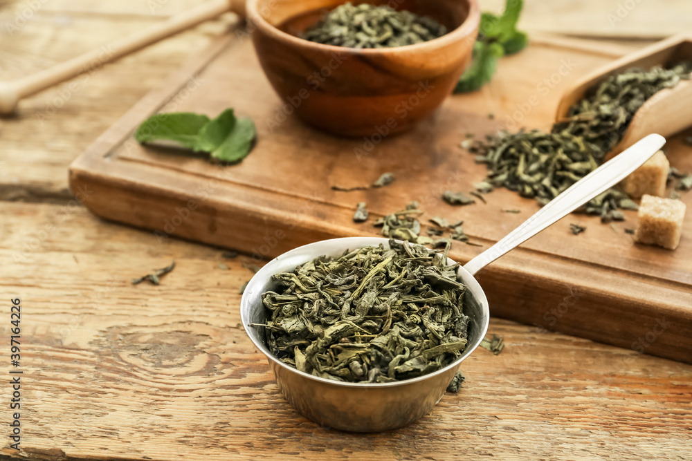 Scoop with dry green tea on wooden table Scoop with dry green tea on wooden table