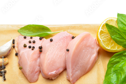 Raw cut chicken fillet with basil and black pepper on white background