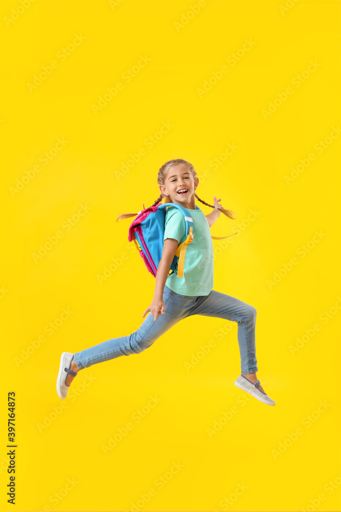 Jumping little schoolgirl on color background
