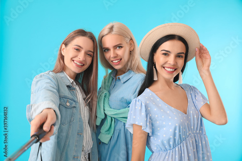 Beautiful young women taking selfie on color background