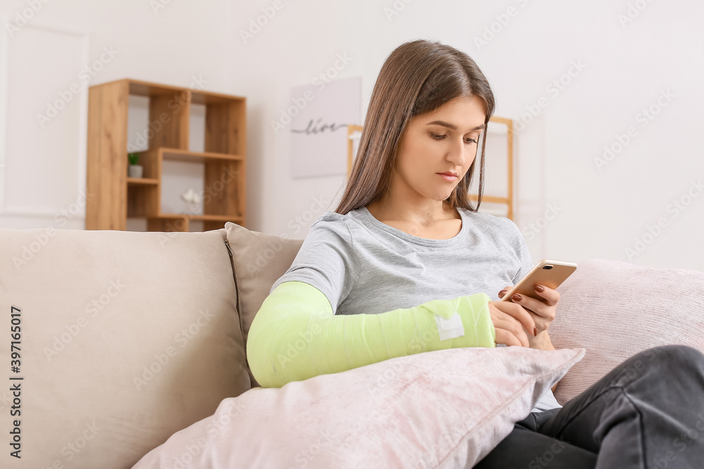 Young woman with broken arm using mobile phone at home Young woman with broken arm using mobile phone at home