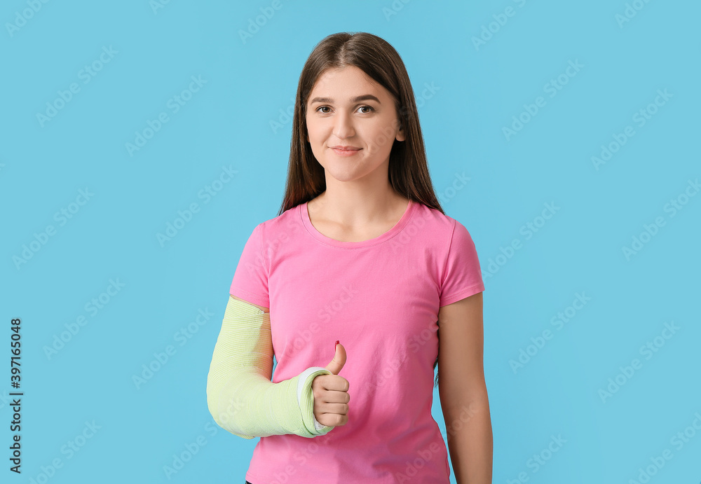 Young woman with broken arm on color background
