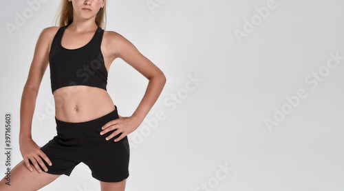 Cropped shot of cute sportive girl child in black sportswear posing isolated over white background