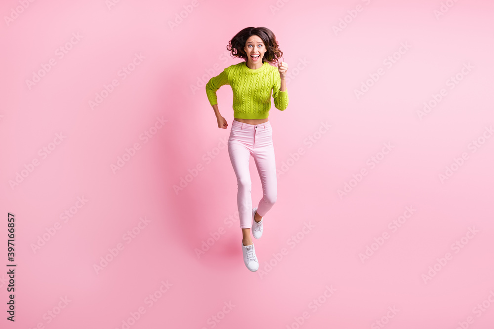 Full length photo of purposeful curly woman dressed green pullover jumping running isolated pastel pink color background Full length photo of purposeful curly woman dressed green pullover jumping running isolated pastel pink color background