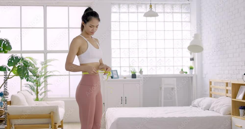happy young woman measuring her waist with measurement tape happy young woman measuring her waist with measurement tape