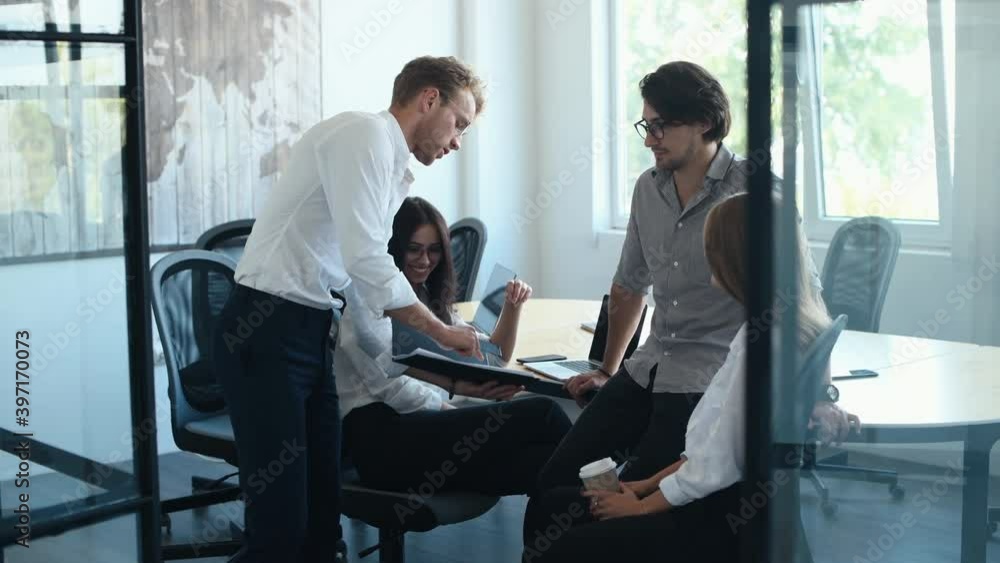 Guy standing and talking to colleagues. Young business people in formal clothes working in the office. Guy standing and talking to colleagues. Young business people in formal clothes working in the office.