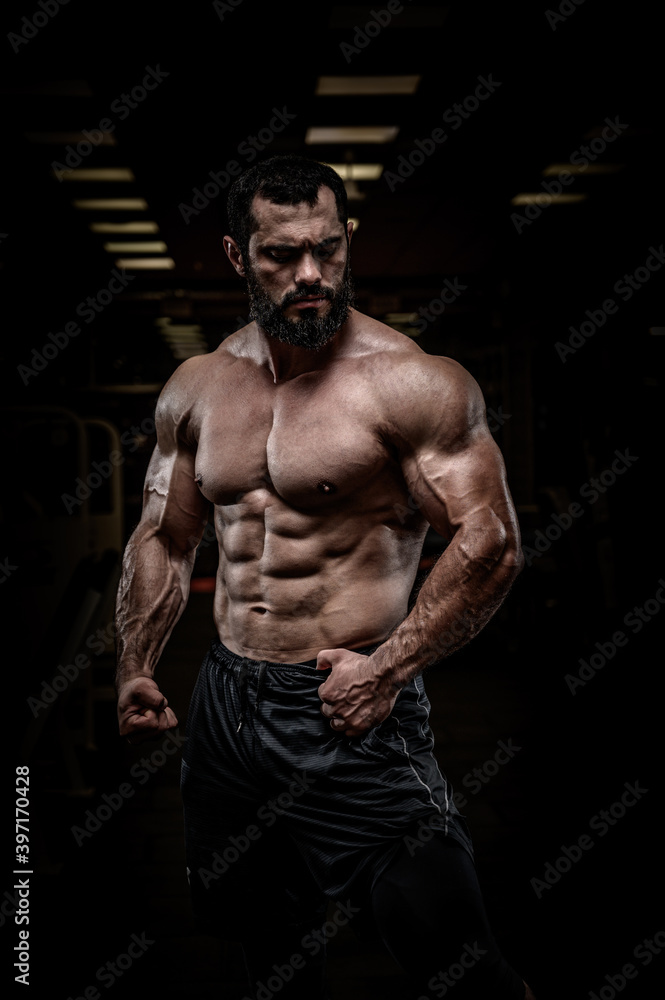 Fototapeta premium strong young bearded athlete male with perfect sport physique body torso muscle in dark fitness gym