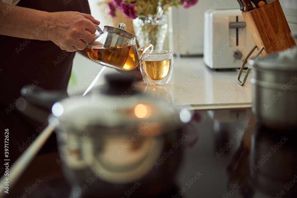 Elderly woman pouring herbal tea into cup