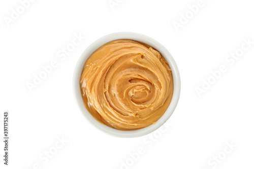 Bowl of peanut butter isolated on yellow background, top view