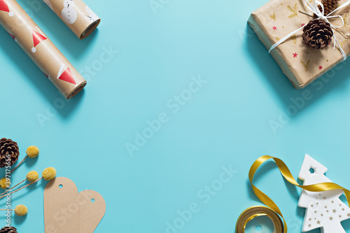 Christmas composition on pastel blue background with white christmas tree, gift boxes, gold ribbon and pine cone. Minimal, flat lay with copy space.