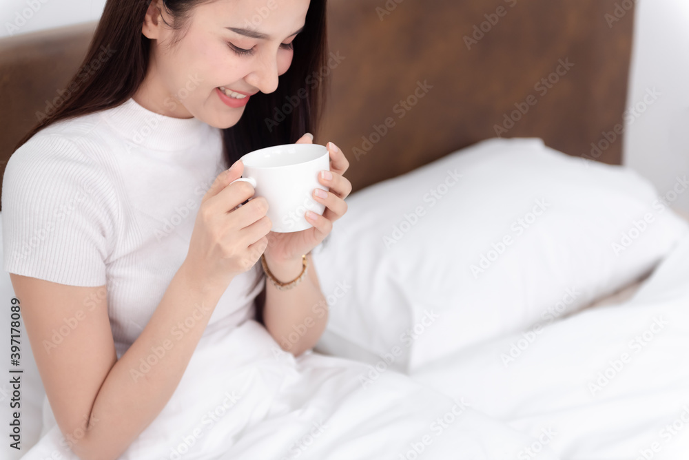 Beautiful asian woman Drinking coffee And happy smile On the bed in the white bedroom Beautiful asian woman Drinking coffee And happy smile On the bed in the white bedroom