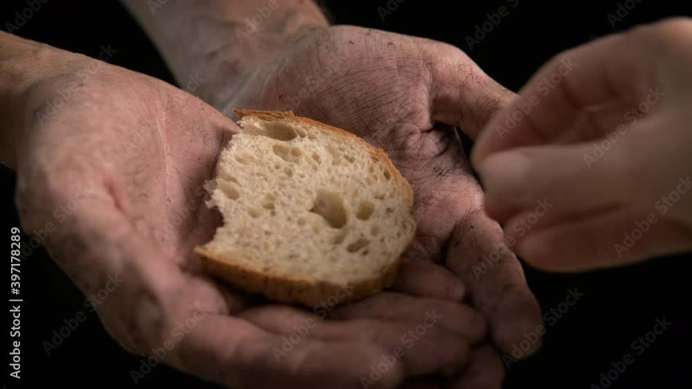 Beggar with bread. A view of a man beggar with dirty hand. A woman gives a piece of bread to the man. Beggar with bread. A view of a man beggar with dirty hand. A woman gives a piece of bread to the man.
