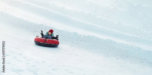 Child loving sledding down a steep hill during a snowly winter.