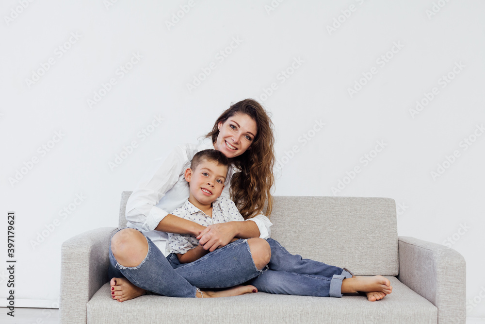 Mom and young son sit at home on a white sofa Mom and young son sit at home on a white sofa