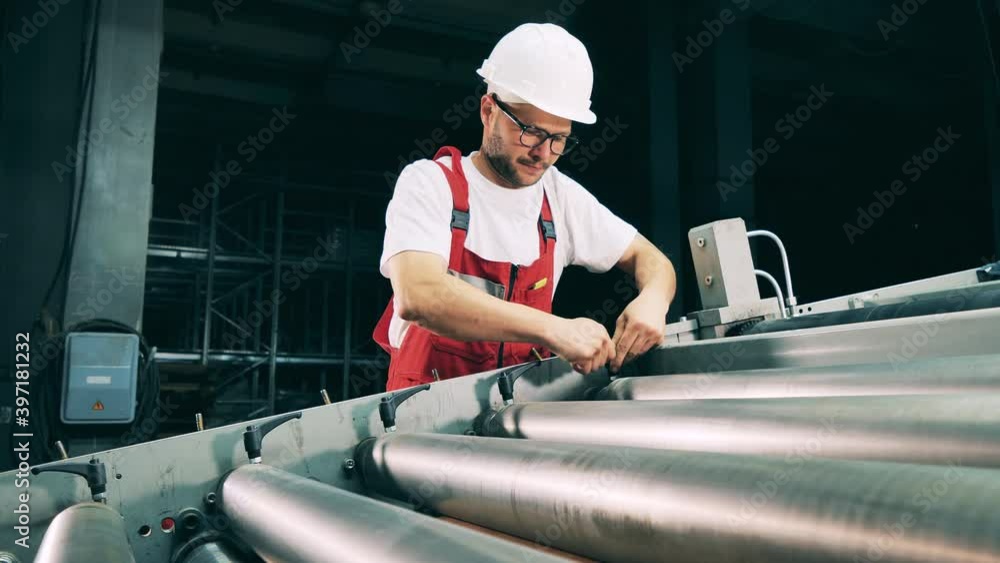 Worker regulating pressure rollers at rolling mill Worker regulating pressure rollers at rolling mill