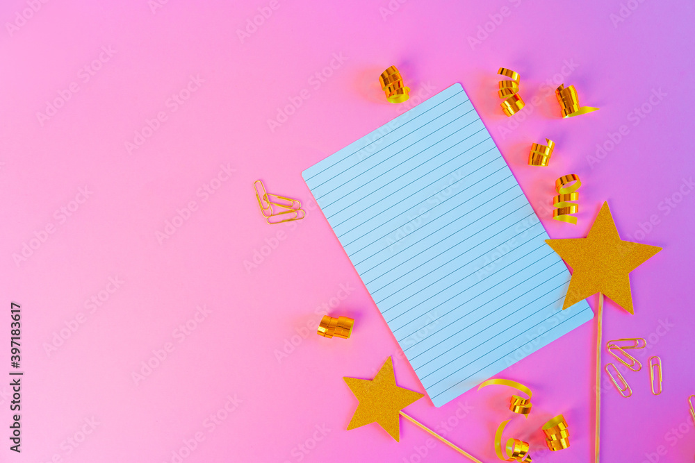 Notepad paper with golden ribbons and gold stars on pink background