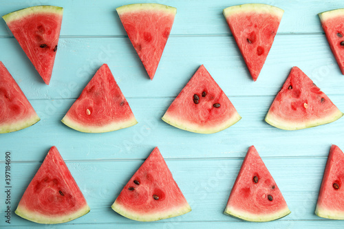 Slices of ripe watermelon on light blue wooden table, flat lay