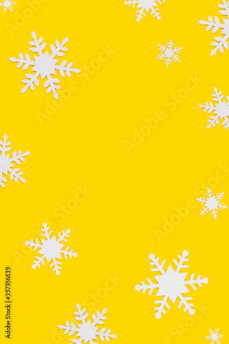 vertical christmas background: many white wooden toys in the form of snowflakes on yellow. Copy Space Center