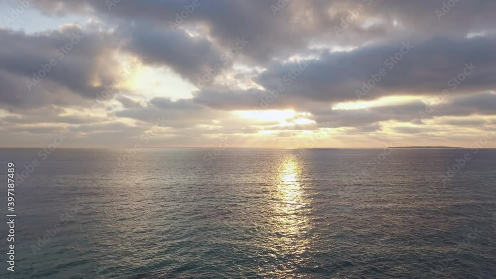 Sun rays peeking through the clouds above the calm sea Sun rays peeking through the clouds above the calm sea
