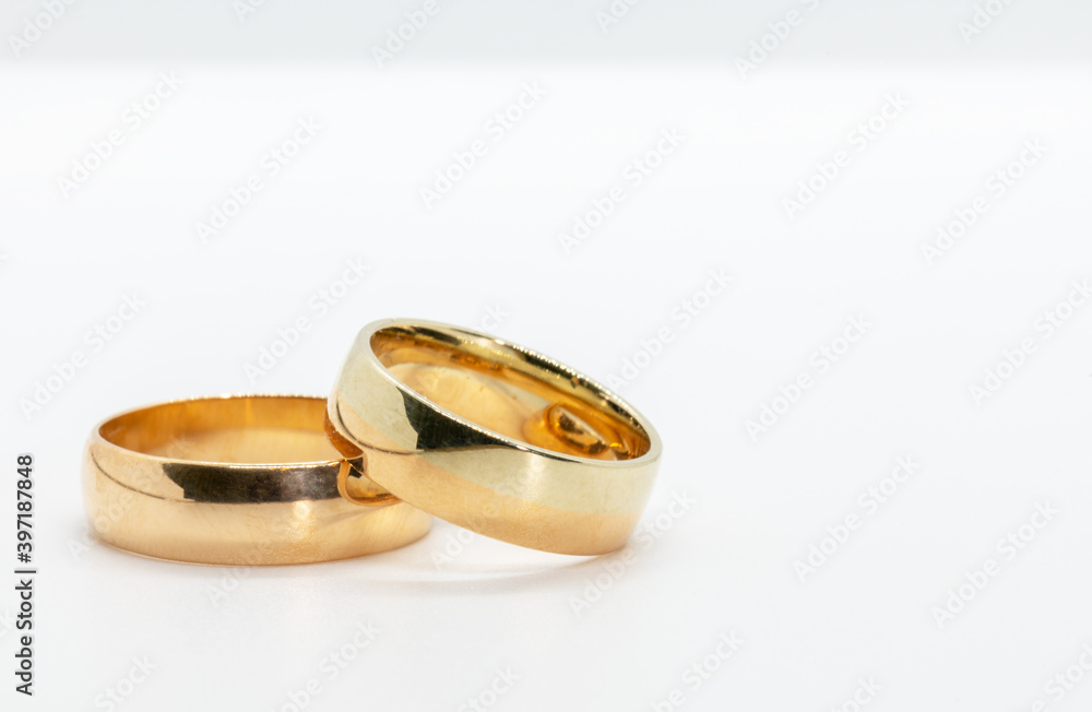 two wedding rings, one on top of the other lying on a white background two wedding rings, one on top of the other lying on a white background