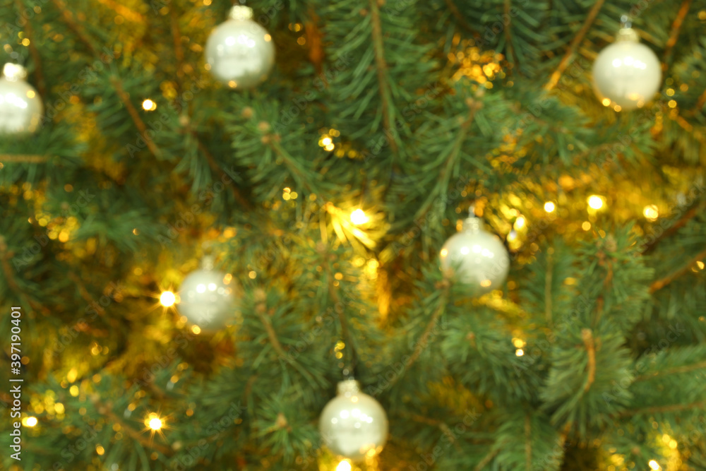 Blurred view of glowing fairy lights and beautiful baubles on Christmas tree