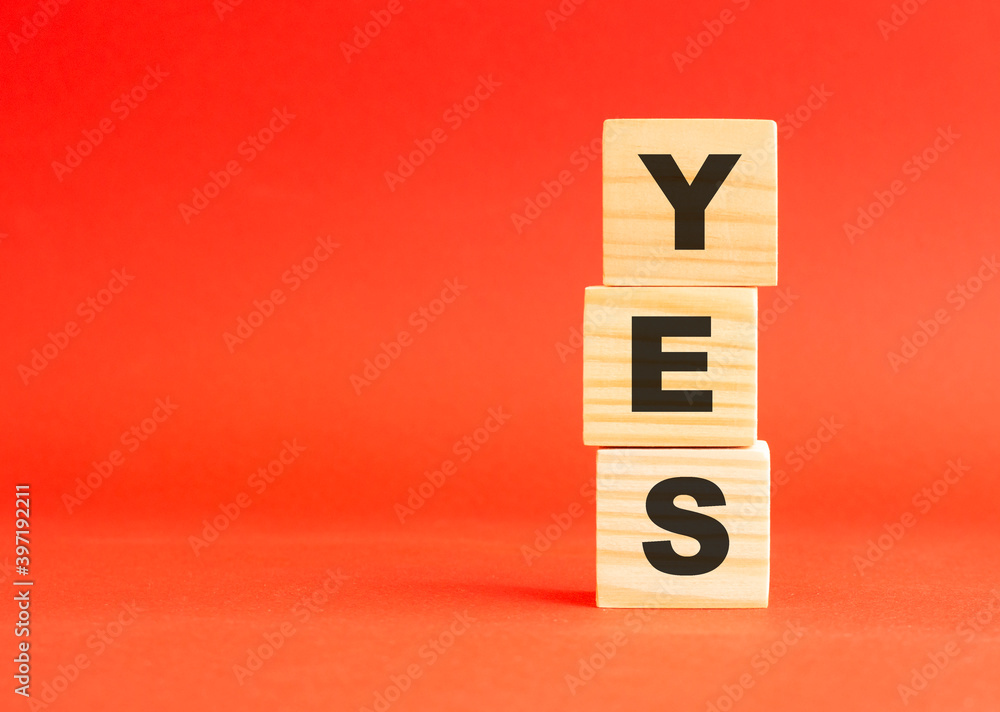 Wooden cubes with word YES. Wooden cubes on a red background. Free space on the left. Wooden cubes with word YES. Wooden cubes on a red background. Free space on the left.