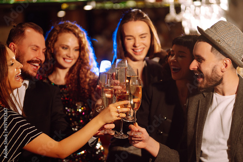 Group of happy people clinking glasses of champagne at party. Young friends celebrating winter holiday together with champagne. Party, celebration, drink, birthday concept.