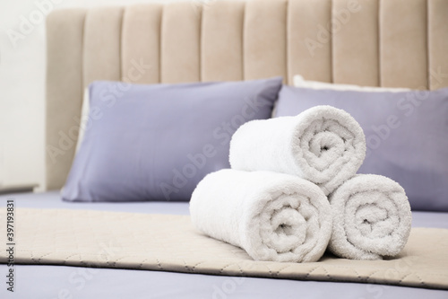 Rolled soft clean towels on bed indoors. Space for text