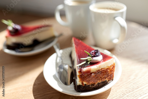 food, junk-food, culinary, baking and holidays concept - piece of delicious cherry chocolate layer cake on saucer with spoon on wooden table