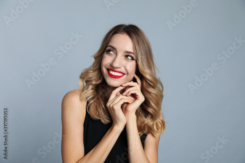 Happy young woman on grey background. Christmas celebration