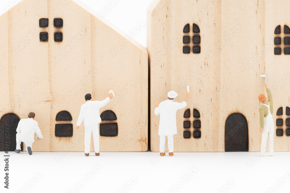 Fototapeta premium Miniature painter is painting the model wooden house.