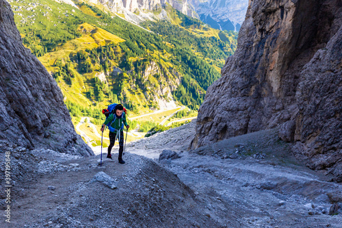 Woman hiking steep rocky mountain trail under cliffs