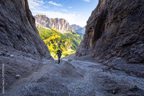 Woman hiking steep rocky mountain trail under cliffs