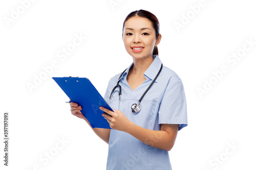 medicine, profession and healthcare concept - happy smiling asian female doctor or nurse in blue uniform with clipboard and pen over white background