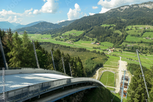 A view from a top of ski jumping hill at Bad Mitterndorf, in the Styrian part of Salzkammergut, Austria, during the summer. The surrounding of the jumping hill is overgrown with lush green plants photo