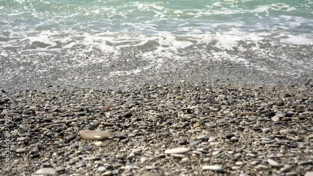 Sea rocky coast with small pebbles, blue sea and waves Sea rocky coast with small pebbles, blue sea and waves
