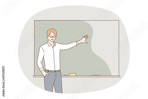 Teaching in school, teacher, education concept. Young positive man teacher cartoon character standing and showing information on blackboard with hand for students during lesson in university