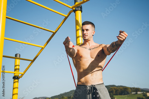 Young man stretching a resistance rubber band before calisthenics training