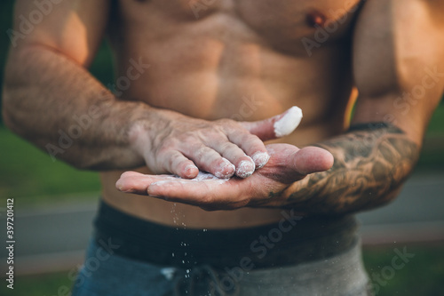 Fotografie Young urban bodybuilder coating his hands with magnesium chalk for calisthenics