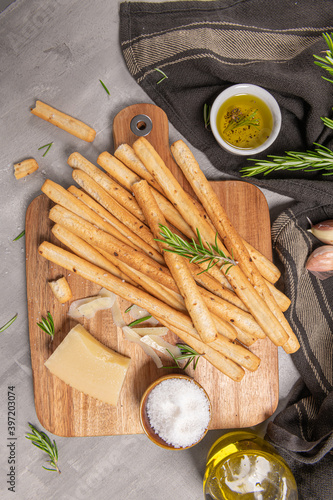 Traditional italian breadsticks grissini with rosemary, parmesan cheese, olive oil, garlic and salt on a gray background. top view. Flat lay with copy space photo