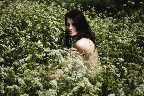Young woman with black hair and naked back among wildflowers