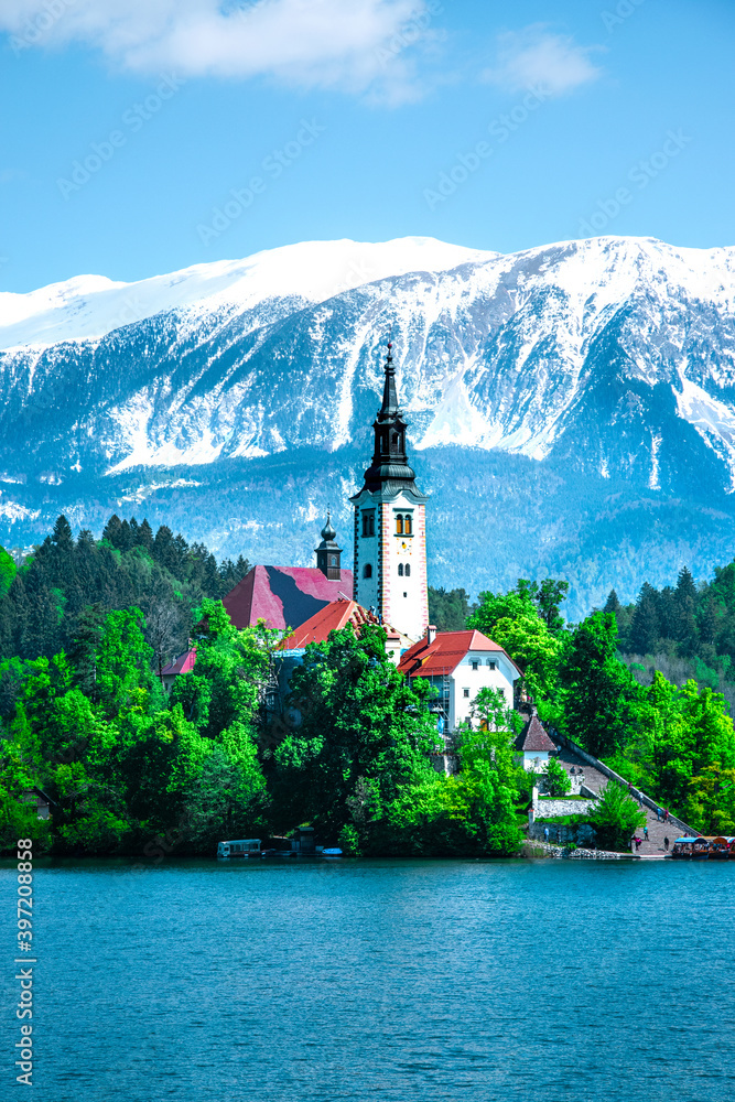 Beautiful and spectacular Julian Alps and Lake Bled. An island on a lake and snow-capped mountain peaks in the background. Slovenia