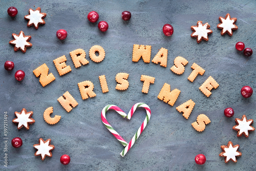 Text Zero Waste Christmas made from cookies. Xmas top view. Minimal design with candy canes, star cookies and fresh cranberry, Natural Christmas decorations on grey aged background. Text Zero Waste Christmas made from cookies. Xmas top view. Minimal design with candy canes, star cookies and fresh cranberry, Natural Christmas decorations on grey aged background.