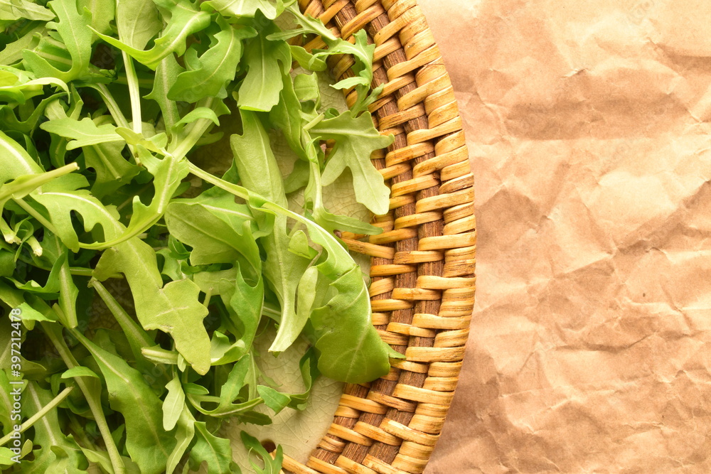 Green ripe organic arugula in a ceramic bowl, close-up, on brown paper. Green ripe organic arugula in a ceramic bowl, close-up, on brown paper.